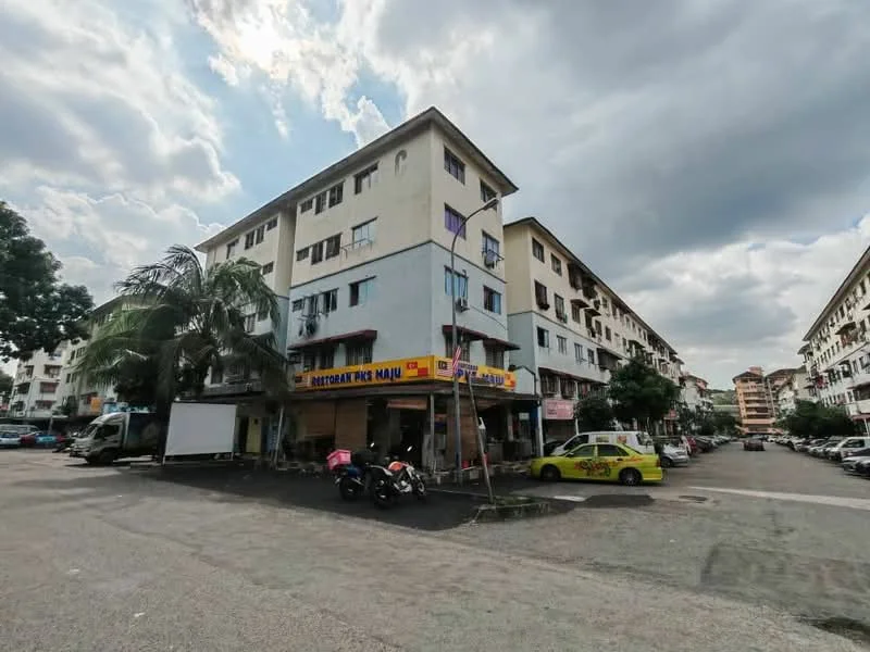 Exterior type: low-rise apartment block; features: 3-storey building, mixed-use ground floor with commercial space, paved parking area, surrounded by palm trees, multiple parked cars, residential units above commercial space, balconies on upper floors, cloudy sky; style: modern.
