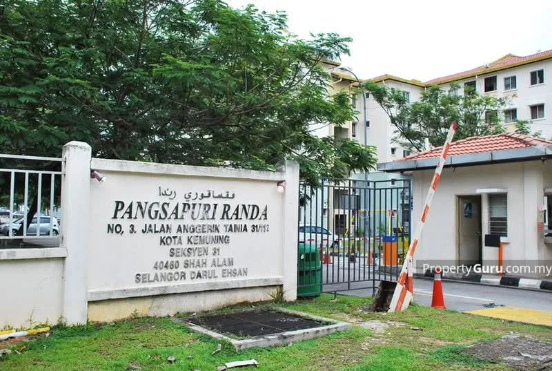 Exterior type: low-rise apartment block; features: white painted facade, gated entry, security boom gate, landscaped garden, surrounded by mature greenery, parking area, signage with property name, multiple storeys visible; style: modern.