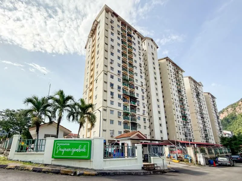 Exterior type: high-rise condominium; features: white painted facade, balconies on each floor, surrounded by palm trees, gated entrance with security, multiple storeys, visible parking area, landscaped garden area, mountain view in background; style: modern.