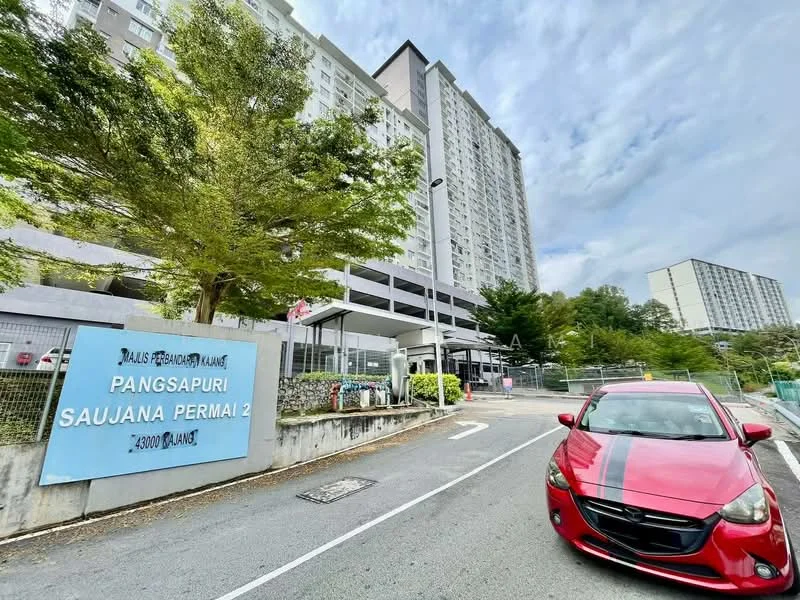 Exterior type: high-rise condominium; features: modern facade, glass curtain wall, landscaped entrance, security guardhouse, gated entry, surrounded by greenery, driveway with interlocking pavers, parking area, signage at entrance; style: modern.