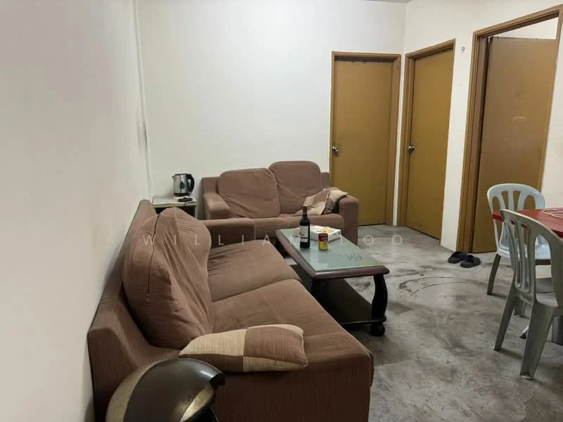 Living features: two brown fabric sofas, coffee table, floor lamp, grey dining chairs, dining table, kettle, concrete flooring, white painted walls, two wooden doors, slippers on the floor.