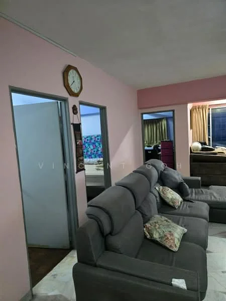 Living features: grey fabric sofa, decorative cushions, wall clock, pink painted walls, doorway leading to another room, doorway leading to bathroom, curtains, tile flooring.