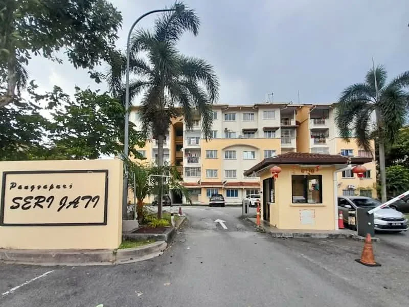 Exterior type: low-rise apartment block; features: yellow painted facade, guard house at entrance, palm trees, manicured landscaping, parking area, signage with 'Seri Jati', multiple storeys, balconies visible, entrance driveway; style: modern.
