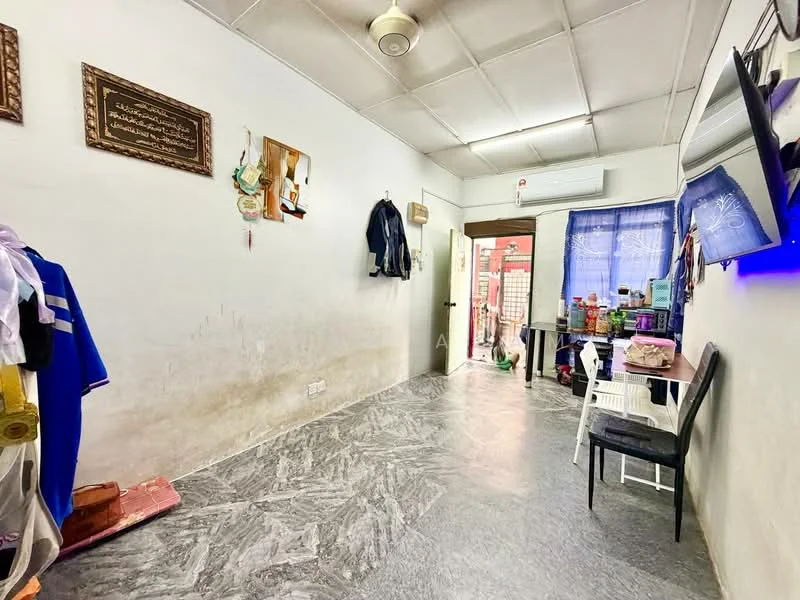 Room features: white painted walls, grey marble flooring, ceiling fan, wall-mounted TV, window with blue curtain, door leading to outside, clothes hanging on wall, plastic chair, various items on shelves.