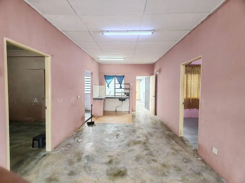 Room features: pink painted walls, concrete flooring, fluorescent ceiling lights, open layout, multiple doorways, window with blinds, kitchen area visible, shelves against wall.