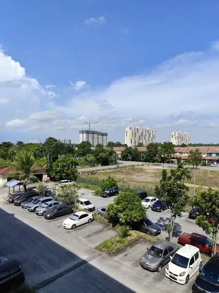 Exterior features: open-air parking lot, landscaped greenery, surrounding residential buildings, construction site in background, clear blue sky, paved road.