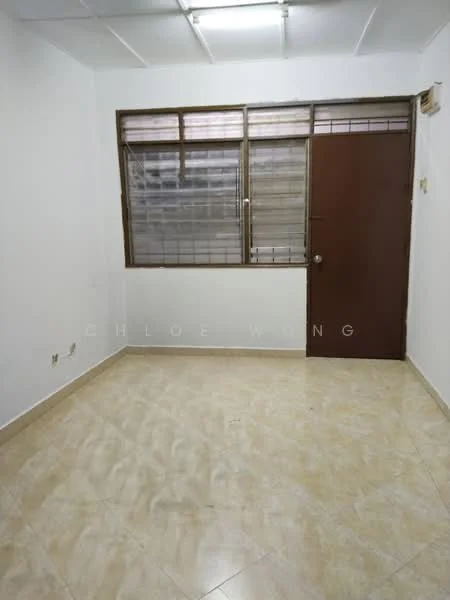 Room features: white painted walls, cream tiled flooring, single wooden door, large window with metal grilles, natural light from window, no visible furniture, plain ceiling, no visible ceiling fixtures; style: minimalist.