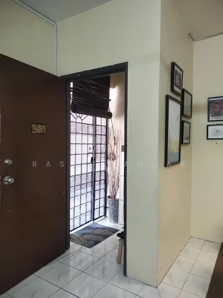 Room features: brown wooden door, white painted walls, white tiled flooring, decorative wall frames, doorway leading to outdoor area, mat at entrance, indoor plant in pot, window with blinds; style: modern.