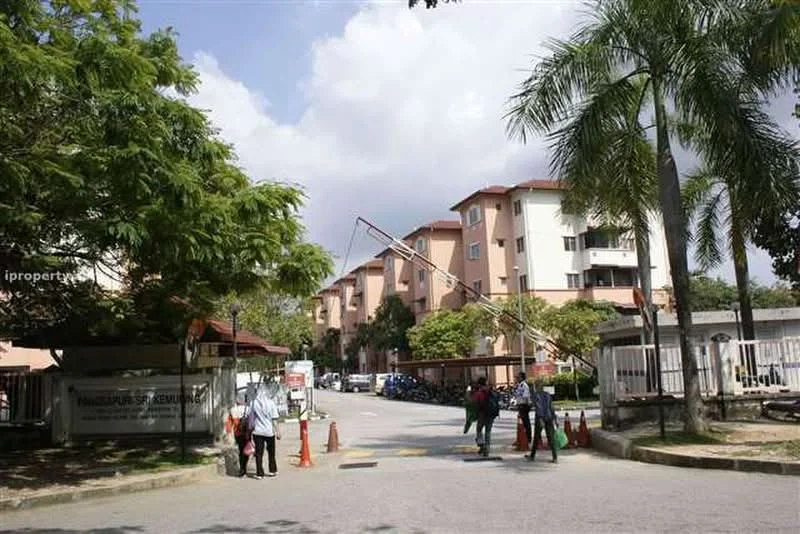 Exterior type: low-rise apartment block; features: cream painted facade, 2-storey building, palm trees, manicured landscaping, guard house at entrance, boom gate, open-air parking lot, surrounded by greenery; style: modern.