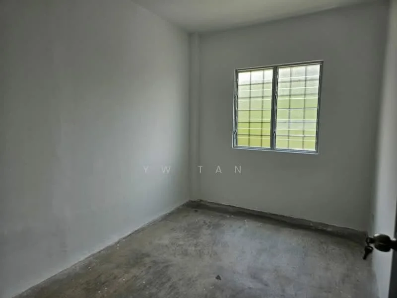 Room features: white painted walls, concrete flooring, single window with metal grille, no visible furnishings or decor.