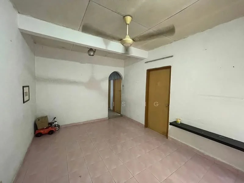 Room features: white painted walls, plain ceiling, ceiling fan, pink tiled flooring, wooden door, arched doorway, shelf along the wall, small toy car, box in corner.