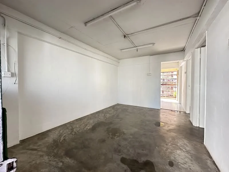 Room features: white painted walls, concrete flooring, exposed ceiling with beams, doorway leading to another room, natural light from doorway; style: minimalist.