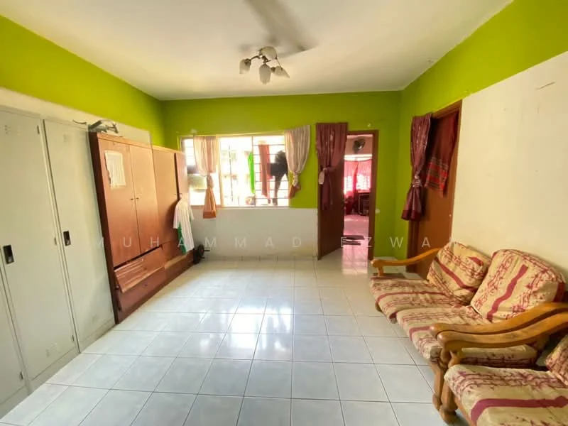 Room features: green painted walls, white tiled flooring, ceiling fan, two-seater sofa with floral pattern, wooden armchair, built-in wardrobe with sliding doors, window with sheer curtains, door leading to another room.