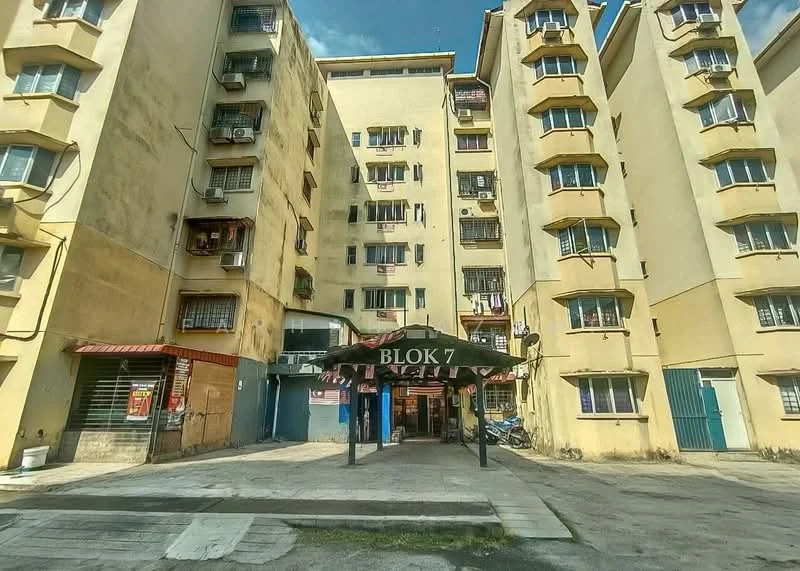 Exterior type: low-rise apartment block; features: cream painted facade, recessed balconies, multiple storeys, main entrance with canopy, ground-level parking area, visible air conditioning units, windows with metal grilles; style: modern.