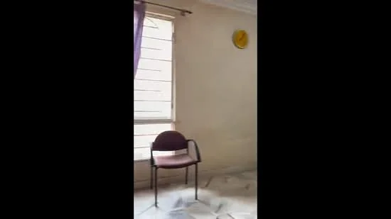 Room features: single chair, window with blinds, clock on wall, marble flooring, cream painted walls.