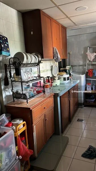 Kitchen features: brown wooden cabinetry, grey countertop, stainless-steel sink, chrome faucet, white ceramic plates on rack, toaster, electric kettle, microwave, blender, fridge, tile flooring, green tiled backsplash, wall-mounted storage, open shelving, plastic storage containers.