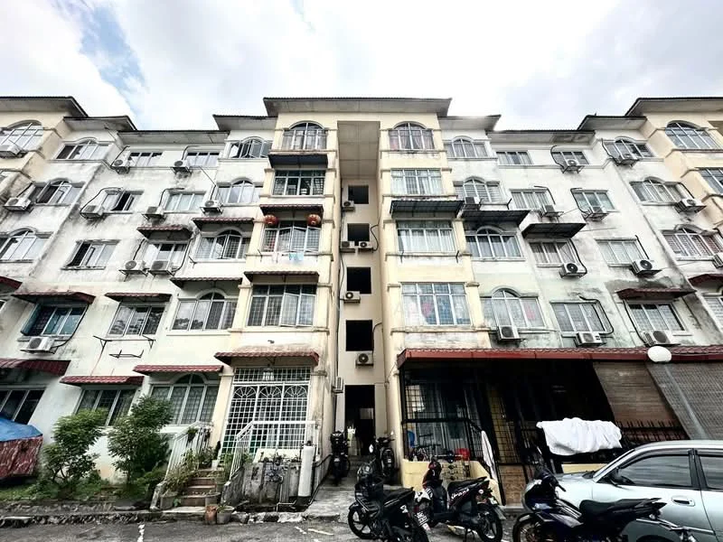 Exterior type: low-rise apartment block; features: cream painted facade, multiple balconies with metal railings, window air conditioning units, ground floor parking area, entrance gate, manicured shrubs, motorcycles parked in front, visible laundry hanging on balconies; style: traditional.