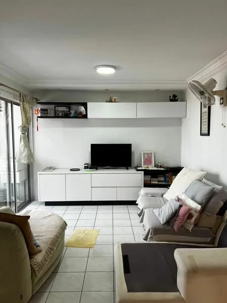 Living features: white painted walls, tile flooring, recessed ceiling light, wall-mounted TV, white TV console, shelf above TV with decorative items, 2-seater fabric sofa in beige, 3-seater fabric sofa in light grey, throw pillows in various colors, floor mat in yellow, sliding glass door leading to balcony, ceiling fan; style: modern; view: city.