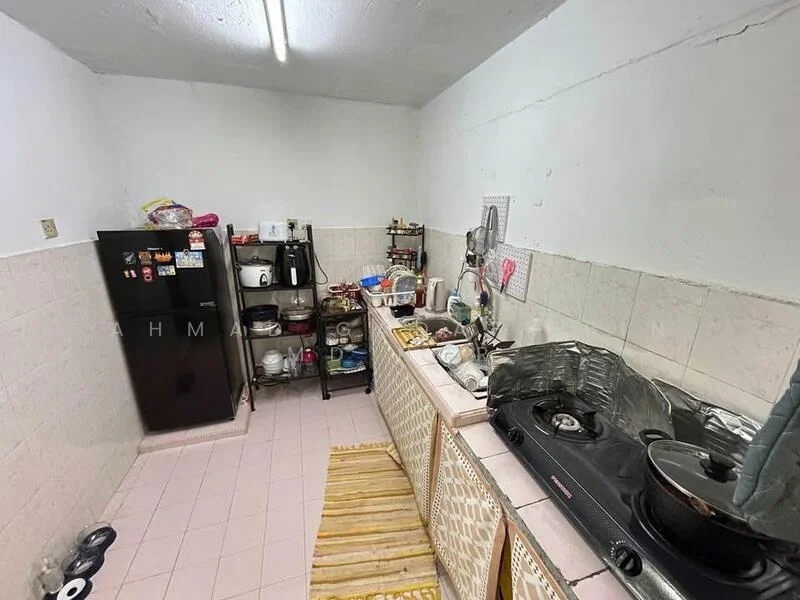 Kitchen features: black refrigerator, stainless-steel gas stove, stainless-steel sink, white tiled backsplash, laminate countertop, wooden cabinetry, open shelving, pink tiled flooring, kitchen utensils on countertop, cooking pots on stove, dish rack, microwave, small kitchen appliances.