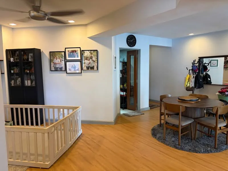 Living features: light wood laminate flooring, white painted walls, 5-blade ceiling fan with light, round dining table, 4 wooden dining chairs, area rug with circular pattern, black shelving unit with framed photos, wall clock, coat rack with bags, doorway leading to another room; style: modern.