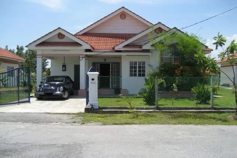 Exterior type: detached bungalow; features: pink painted facade, red tiled roof, single-storey, manicured lawn, fenced yard, paved driveway, car porch, front garden with shrubs, gated entrance, windows with white frames, porch area, decorative wall light; style: modern.