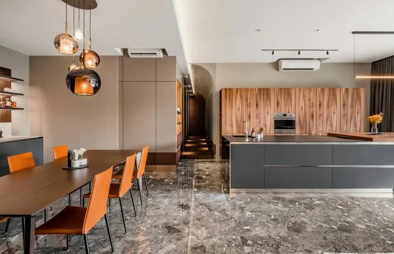 Kitchen features: marble flooring, grey cabinetry, wooden cabinetry, island countertop, built-in oven, stainless-steel range hood, 5-blade ceiling fan, recessed downlights, pendant lighting, open shelving, dining table with 6 orange chairs, wall-mounted split AC; style: modern.