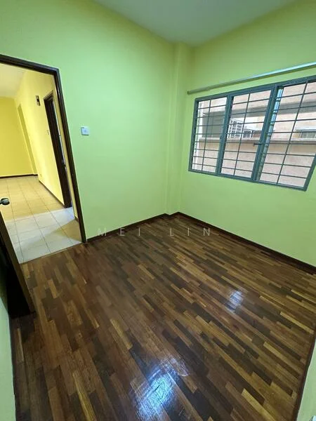 Room features: yellow painted walls, wooden flooring, single window with metal grille, doorway leading to another room, light switch on wall, neutral ceiling, no visible furniture.