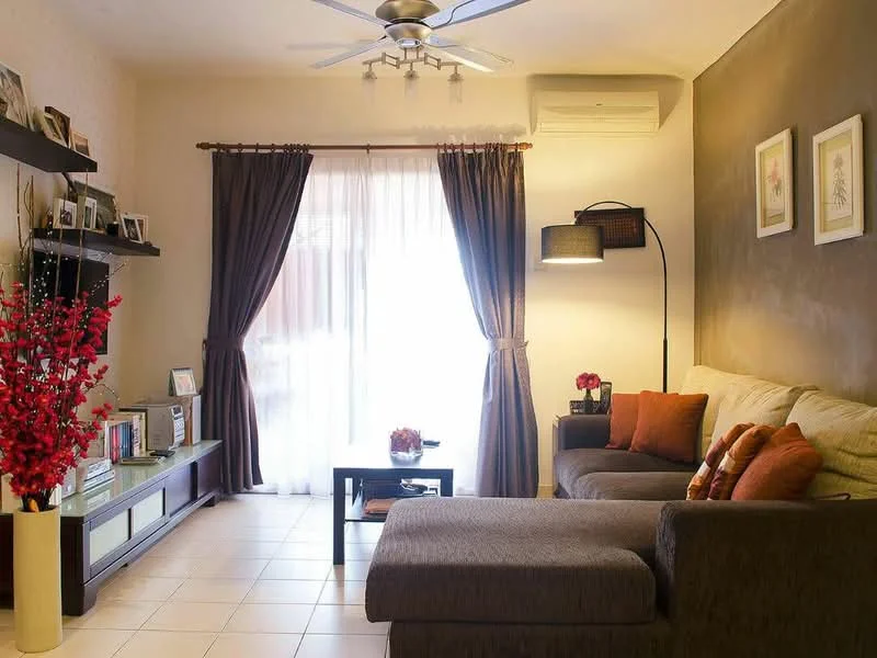 Living features: 3-seater fabric sofa in beige, chaise lounge, coffee table, wall-mounted TV, TV console, decorative floor lamp, 5-blade ceiling fan with light, curtains in dark brown, light-colored walls, accent wall in dark grey, tile flooring, decorative wall art, houseplants in ceramic pots, red floral arrangement in vase; style: contemporary; view: garden.