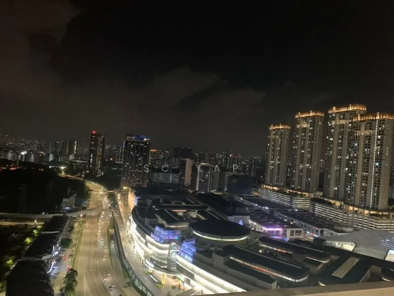 Exterior type: high-rise condominium; features: city skyline view, night lighting on buildings, surrounding urban landscape, multiple high-rise buildings, main road visible, shopping complex in foreground; style: modern.