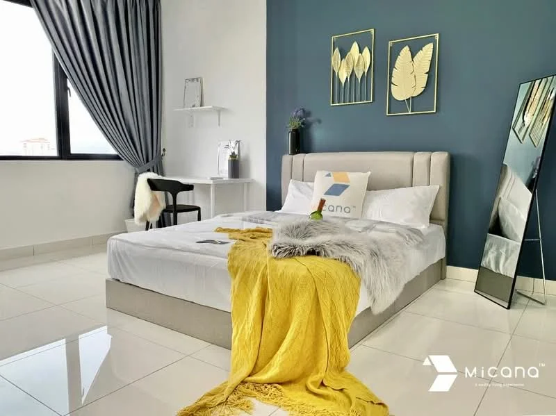 Bedroom features: king-size bed with upholstered headboard, white bedding, yellow throw blanket, decorative pillow with logo, mirrored full-length mirror, grey accent wall, white painted walls, floor-to-ceiling window with sheer curtains, white bedside table, black chair, ceramic vase with plant, polished tile flooring; style: modern; view: city.