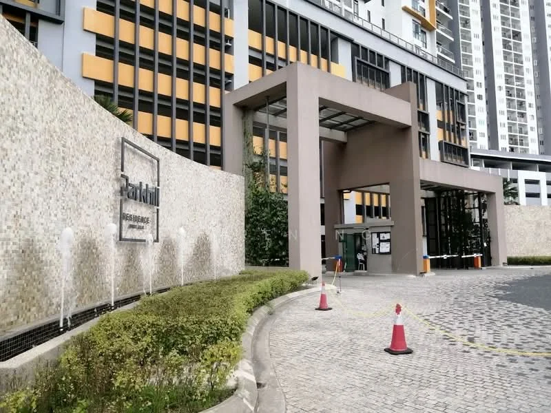 Exterior type: high-rise condominium; features: modern facade with stone cladding, glass curtain wall, water feature at entrance, landscaped garden with shrubs, paved driveway, security guardhouse at entrance, covered entrance, visible signage, surrounded by greenery; style: modern.