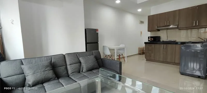 Living features: grey fabric sofa, glass coffee table, white dining table, white dining chairs, stainless-steel fridge, built-in kitchen cabinets in brown, black countertop, microwave, freestanding washing machine, recessed downlights, cream painted walls, tile flooring; style: modern.