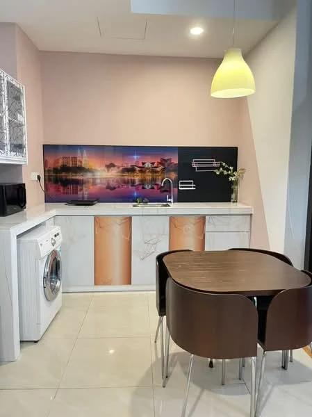 Kitchen features: white cabinetry with marble pattern, grey countertop, stainless-steel washing machine, microwave, wall-mounted TV, pendant light, dining table with four chairs, cream tiled flooring, decorative wall art, pink painted walls; style: modern.