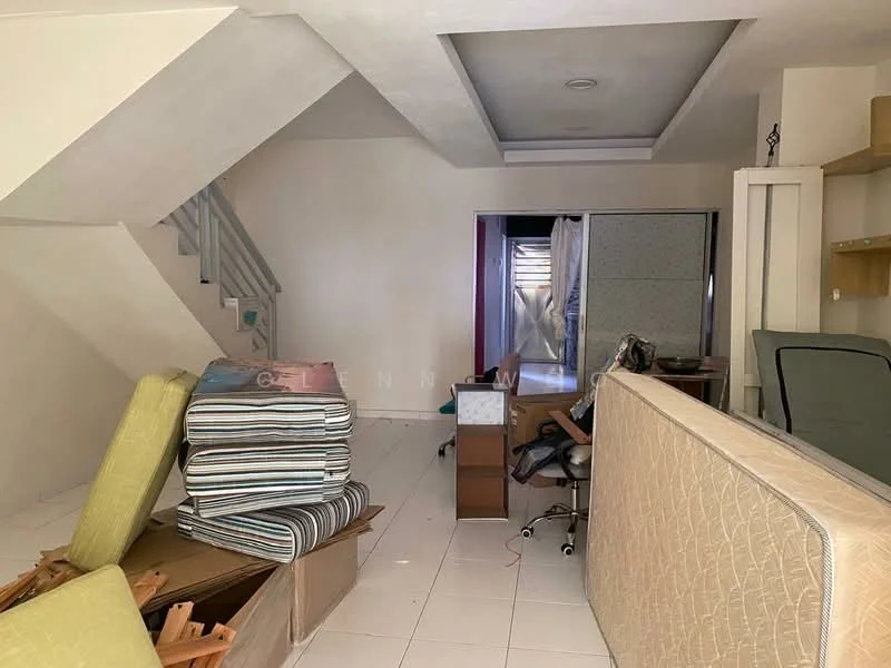 Room features: white painted walls, tile flooring, staircase with wooden railing, open space layout, furniture including a sofa and chairs, cardboard boxes, desk with chair, window with sheer curtains.