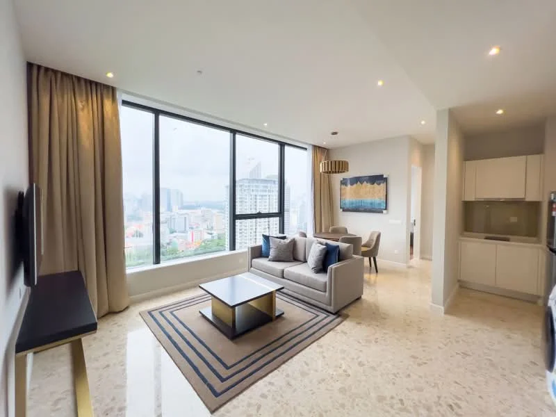 Living features: floor-to-ceiling windows, grey fabric sofa, coffee table with gold accents, area rug with geometric pattern, wall-mounted TV, decorative wall art, recessed downlights, curtains in beige, marble flooring, city view; style: modern; view: city. Kitchen features: white cabinetry, built-in refrigerator, stainless-steel appliances, countertop with bar seating, open layout to living area; style: modern.