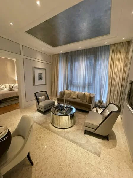 Living features: cream painted walls, exposed ceiling with recessed lighting, large floor-to-ceiling windows with sheer curtains, light-colored sofa with decorative cushions, two accent chairs in grey with dark wood trim, round coffee table with mirrored base, area rug with neutral tones, marble flooring, decorative wall art, wall-mounted mirror, built-in shelving unit; style: modern.