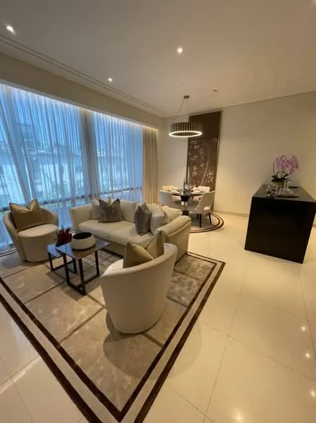 Living features: cream painted walls, polished marble flooring, recessed downlights, chandelier, floor-to-ceiling windows with sheer curtains, 3-seater fabric sofa in white, 2 accent chairs in white, round coffee table with black base, area rug with geometric pattern, decorative wall art, dining table for four, vase with orchids on dining table; style: modern.