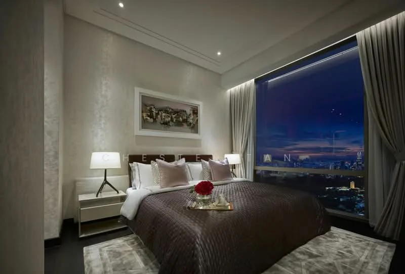 Bedroom features: king-size bed with brown quilted cover, upholstered headboard, two bedside lamps with white shades, framed artwork on wall, floor-to-ceiling window with city view, sheer curtains, dark wood bedside tables, decorative flower arrangement on bedside table, area rug with geometric pattern, recessed ceiling lights; style: modern; view: city.