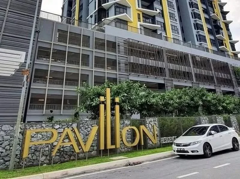 Exterior type: high-rise condominium; features: modern facade with grey and yellow accents, glass curtain wall, landscaped garden with greenery, stone cladding at base, parking deck visible, large signage with 'PAVILION', multiple balconies, surrounding road access; style: modern.