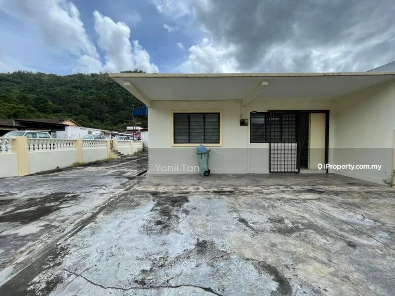 Exterior type: detached bungalow; features: flat roof, cream painted facade, concrete driveway, manicured lawn, single-storey, window grilles, parking space, surrounded by greenery; style: minimalist.