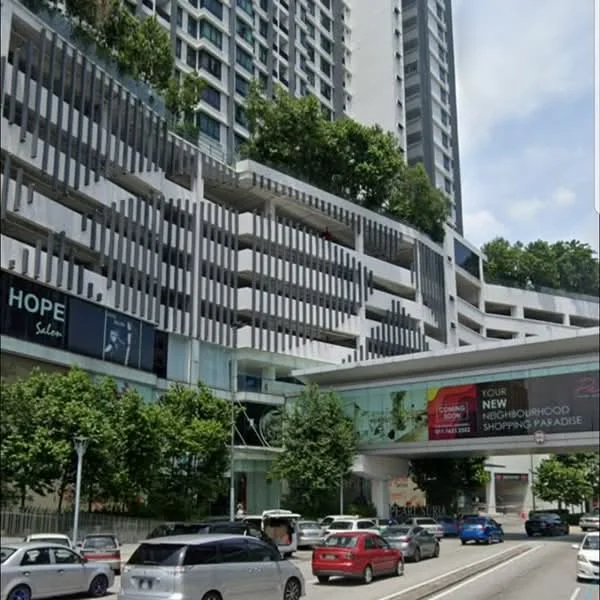 Exterior type: high-rise condominium; features: glass curtain wall, white painted facade, recessed balconies, greenery on balconies, multi-storey car park, landscaped garden at ground level, commercial units at ground level, pedestrian walkway, surrounded by mature trees, urban context with road access; style: modern.
