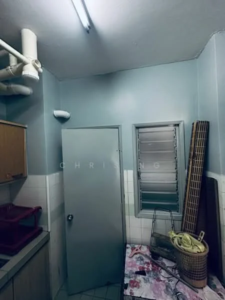 Room features: light blue painted walls, white tiled walls, grey door, sliding window with metal grilles, tile flooring, wooden cabinetry, sink with plumbing, laundry basket, floor mat.