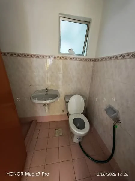 Bathroom features: pink tiled flooring, white painted walls, wall-mounted sink, chrome faucet, toilet, bidet spray, small window, tile border with floral pattern.