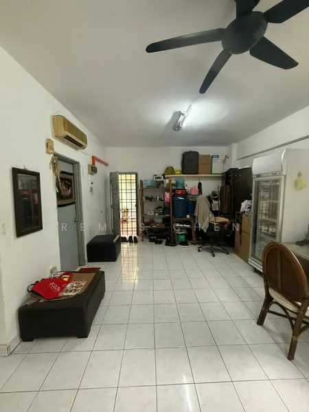 Room features: white painted walls, white tiled flooring, ceiling fan, wall-mounted air conditioning unit, refrigerator, storage boxes, shelves with various items, black ottoman, wooden chair, door leading to another room, light fixture on ceiling.