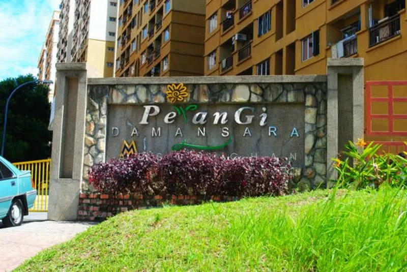 Exterior type: low-rise apartment block; features: stone-clad entrance sign, colorful lettering on sign, landscaped garden with shrubs, yellow gate, surrounding residential building, blue car parked nearby; style: modern.