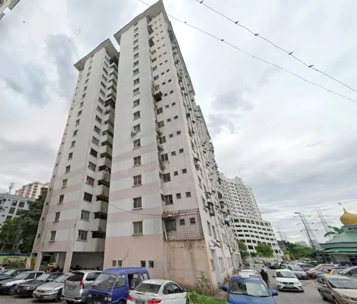 Exterior type: mid-rise condominium; features: pink painted facade, balconies on upper floors, visible parking area, surrounding greenery, multiple storeys, windows with metal grilles; style: modern.