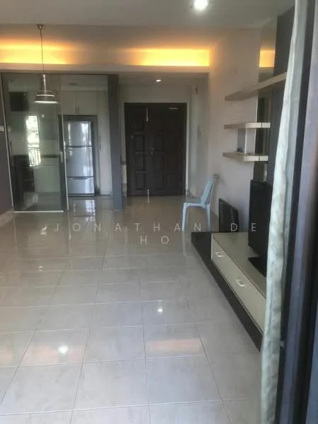 Living features: white painted walls, glossy tile flooring, recessed downlights, built-in shelving unit, TV console, wall-mounted TV, large glass sliding door, open layout to kitchen, single chair, entrance door, fridge visible in kitchen area; style: modern.
