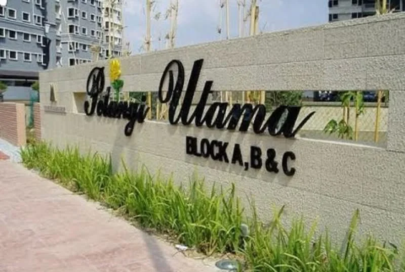 Exterior type: low-rise apartment block; features: concrete wall with signage, landscaped garden with grass, paved walkway, surrounding greenery, modern architectural design, visible apartment blocks in background; style: modern.