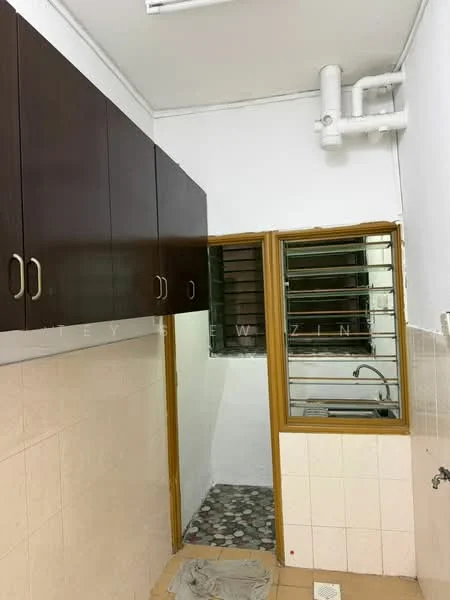 Kitchen features: brown wooden cabinetry, white tiled walls, grey patterned floor tiles, single-bowl stainless-steel sink, window with metal grilles, exposed plumbing, light fixture on ceiling, countertop space.