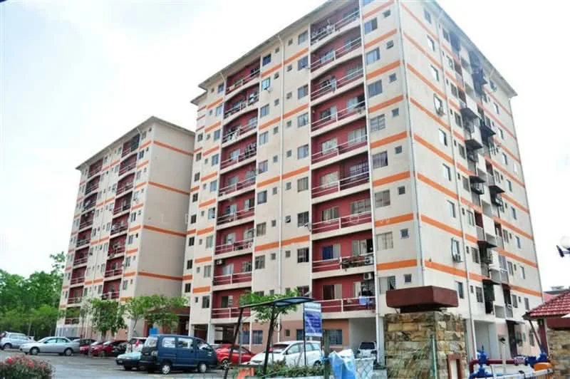 Exterior type: low-rise apartment block; features: cream painted facade, red accent panels, balconies with railings, multiple storeys, parking area visible, landscaped garden in foreground, surrounded by greenery; style: modern.